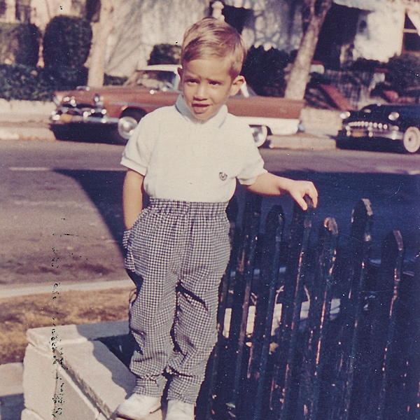 A boy photo of Michael Raff standing next to a fence.